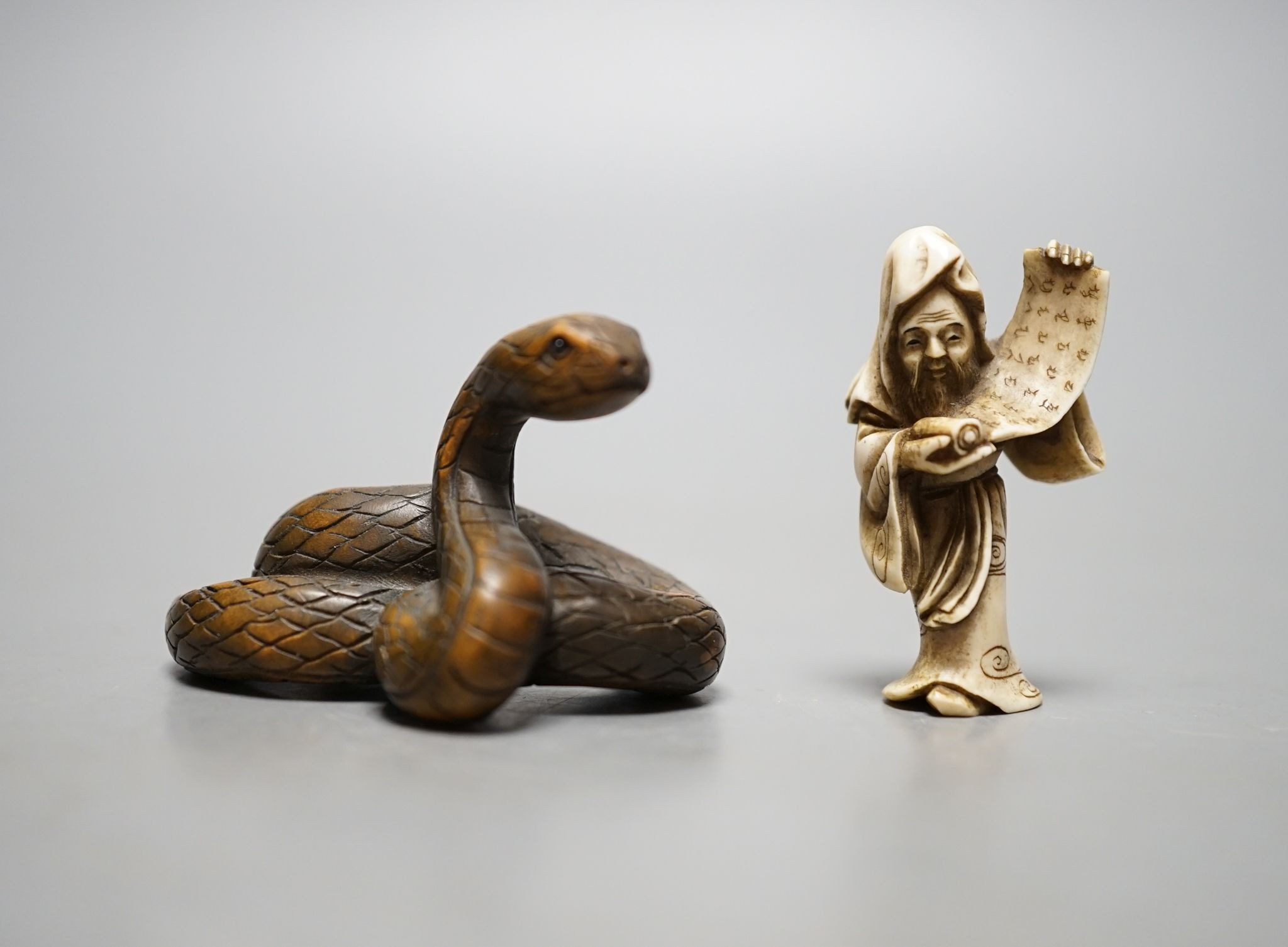 A Japanese ivory figure of a sage and a signed carved wood snake netsuke, 5cm long